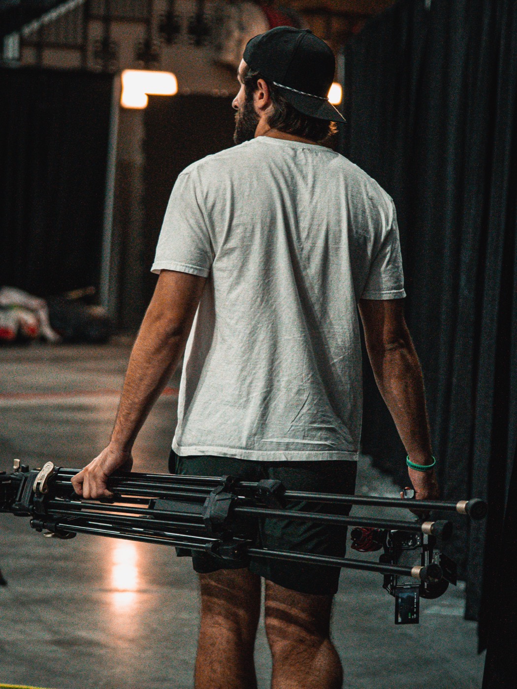 Connor Parish, founder of Parish Media, carrying a tripod and camera rig through an arena tunnel